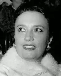 Publicity photograph of a woman in her forties wearing makeup, jewellery and furs, with dark hair tied back.