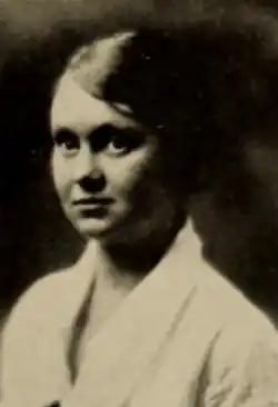 A young white woman wearing a white blouse or jacket with a collar