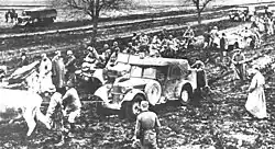 a black and white photograph of troops and animals pulling vehicles out of the mud