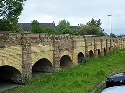 Photograph showing a series of small arche bridges making a low viaduct over dry land