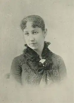 B&W portrait photo of a woman with her hair in an up-do, wearing a dark jacket.