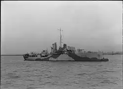 ship at sea steaming from left to right, her guns are unmanned and the bridge crew can be seen