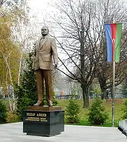 Statue of Aliyev in a park with cyrillic script on plinth below
