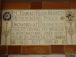 A tablet formed of five tiles of varying sizes, bordered by yellow and blue flowers in an art nouveau style