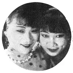 A black-and-white image, cropped in a circle, of two women gazing at the camera