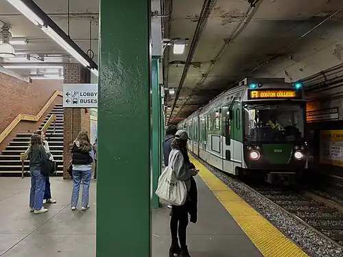 A green light rail train at an underground station
