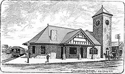 A woodcutting of a stone Romanesque railway station with a square clock tower