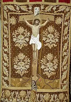 A processional banner in the Sainte-Nonne church depicting Christ's crucifixion. Note the "Ankou" at the base of the cross.