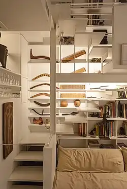 One of the staircases from the third to fourth floors. The stairs appear to float, and there are shelves with objects behind the stairs.