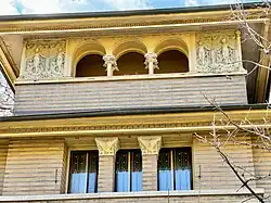Detail of upper-story windows as seen from Woodlawn Avenue. The second-story windows are separated by columns with capitals. The third-story windows are within an arcade with arches.