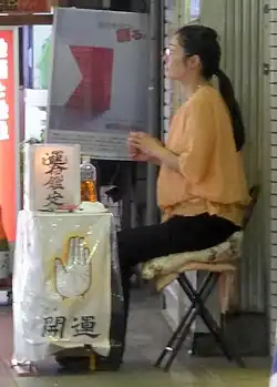 A Japanese palm-reader waits along the street for a customer, 2015