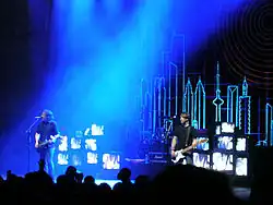 Two men performing onstage playing and singing into a microphone