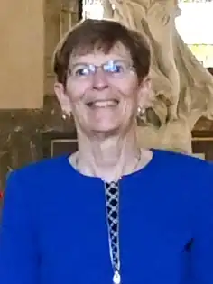 Portrait photo of Donoghue wearing glasses and a blue shirt