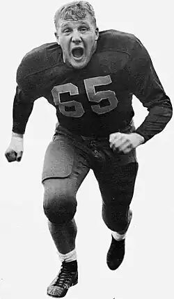 Joe Schmidt running in his Pittsburgh Panthers football uniform with no helmet on and his mouth open.