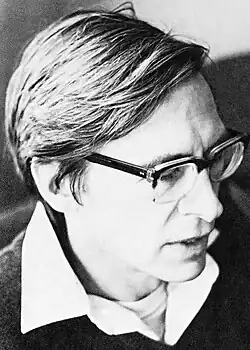Black-and-white photo of a man with glasses wearing a collared shirt under a sweater