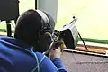 A junior shooter in Switzerland exercising bullseye shooting with a SIG 550. The rifle is equipped with a brass catcher to avoid disturbing other shooters with the ejection.