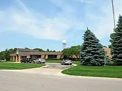 A one-story brick studio building in a landscaped setting. A weather radar is mounted on a short tower at the back of the building. Off to the side is a large, guyed tower.