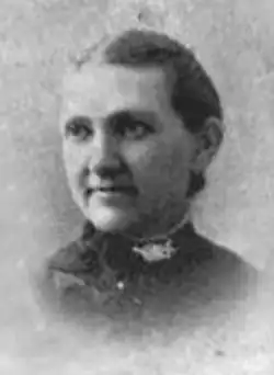 A white woman with hair parted center and combed tightly back to the nape