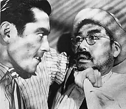 A violent Matsunaga pins Sanada to the wall with his elbow.