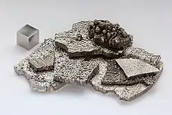 Gray cobalt chips with a small cube of cobalt
