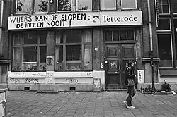 Black and white photograph of Tetterode with a banner saying (in translation) "You can demolish Wyers but not the ideas!"