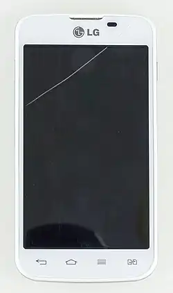 A white touch-screen mobile phone, with a single crack running across the top right corner of the glass that covers the device. The top part of the phone contains a proximity sensor (black) to the right of the speaker (center), and the bottom part includes four capacitive buttons, of which three are Back, Home, and Menu keys.