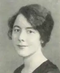 headshot of a dark-haired white woman facing left with a v necked top on and a necklace.