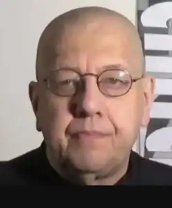 caucasian male with shaved head wearing spectacles