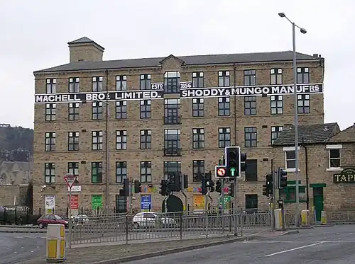 Five story building with many high windows stretching across the background with road and traffic light controlled junction in front