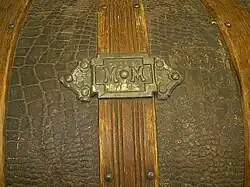 The two "M"s stamped in metal signify the maker of the trunk.