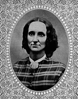 portrait of white woman with brown shoulder-length hair, wearing a plaid outfit in an oval frame