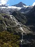 The Hirere Falls on the Milford Track are on the south western extreme of the Wick Mountains. The peaks behind at up to 1,920 metres (6,300 ft) do not have official names.[1]