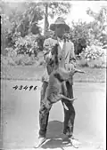 A man holding a dead crab-eating raccoon in Guyana, 1922