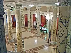 The entrance hall preserves the marble Ionic columns and tile mosaic floors of the original, 1896 Eidlitz design.