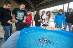 People standing around a pool containing a remotely operated underwater vehicle