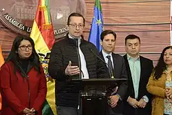 Oscar Ortiz standing at a podium during a press conference.