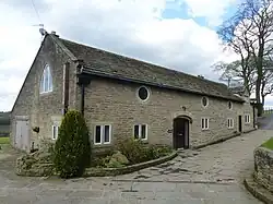 A long stone building with round windows and a former wagon arch
