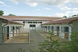 Each stall has a small fenced turnout area; access to each stall is from inside the building