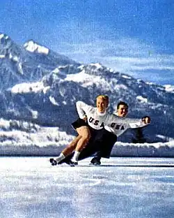 A man and woman in figure skating attire skating on ice.