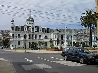 A neo-baroque mansion at the end of a street, with the clear day sky above.