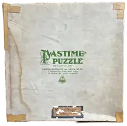 The top of the Pastime Puzzle box from the 750 piece puzzle "The Lute Players." It includes a patent number as well as locations in Salem, Massachusetts, the Flatiron Building in New York, and 12 Whiteley Road, London. There is also a damaged label that suggests this puzzle was previously part of a rental library.