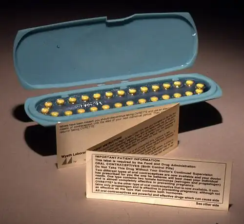 An oblong blue container holding 28 yellow pills, with a small, folded paper note standing in front of it
