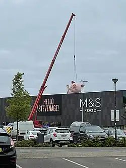 A crane hoisting a giant statue of the Percy Pig character up to the roof of the newly opened store in Stevenage.