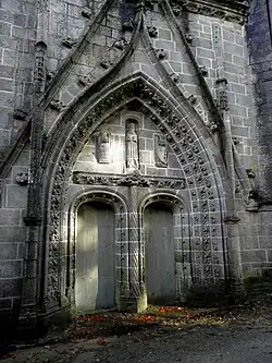 The west façade of the chapel. Saint Herbot is depicted with two angels on either side. The angels carry a banner reading "LAN:M:VC:XVI:/FVT CEST PORTAL/.COMA[N]CE:MESSIR[E]:CHO[RENTIN]:/K[ER]DETFEZ GOVVERNEUR"