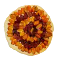 Pizza-sized round tart, with quartered yellow and purple plums arranged in rings