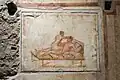 An erotic wall painting on the west wall of a small room at the side of the kitchen from The House of the Vettii, Pompeii. [21]