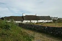 single story white thatched cottage