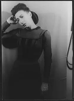 A young woman, standing, in a dark dress