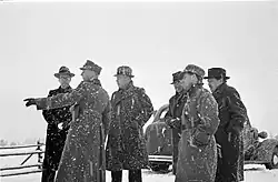 A group of foreign journalists observes something during snowfall in Mainila, where a border incident between Finland and the Soviet Union escalated into the Winter War.