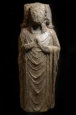 A carved sculpture in Purbeck Marble of a priest on a coffin lid from the Shaftesbury Abbey collection..